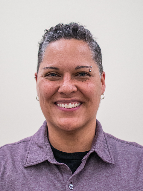 Sarah Pecora smiling, standing in front of white background