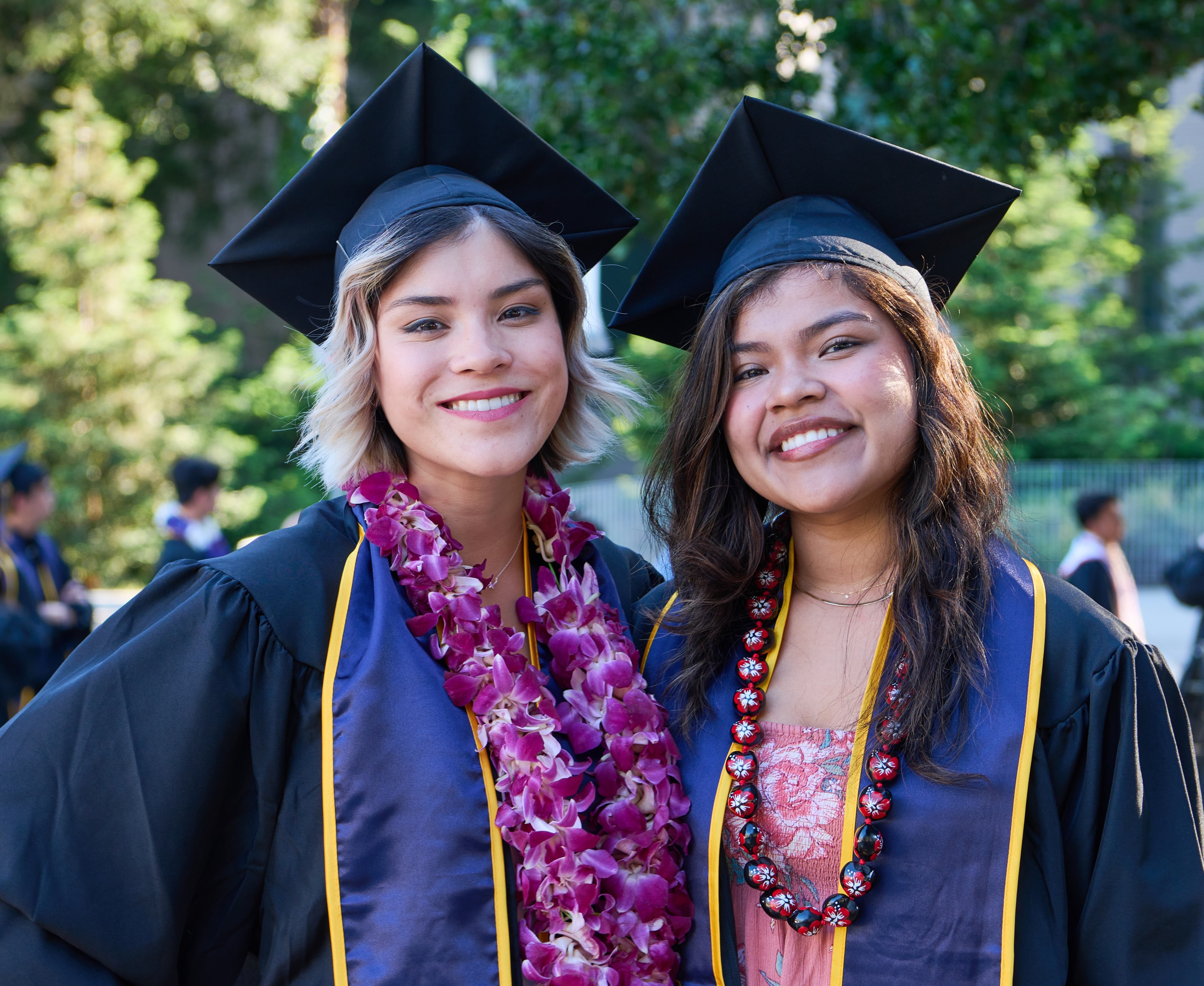 Two latina students pose in graduation caps and gowns