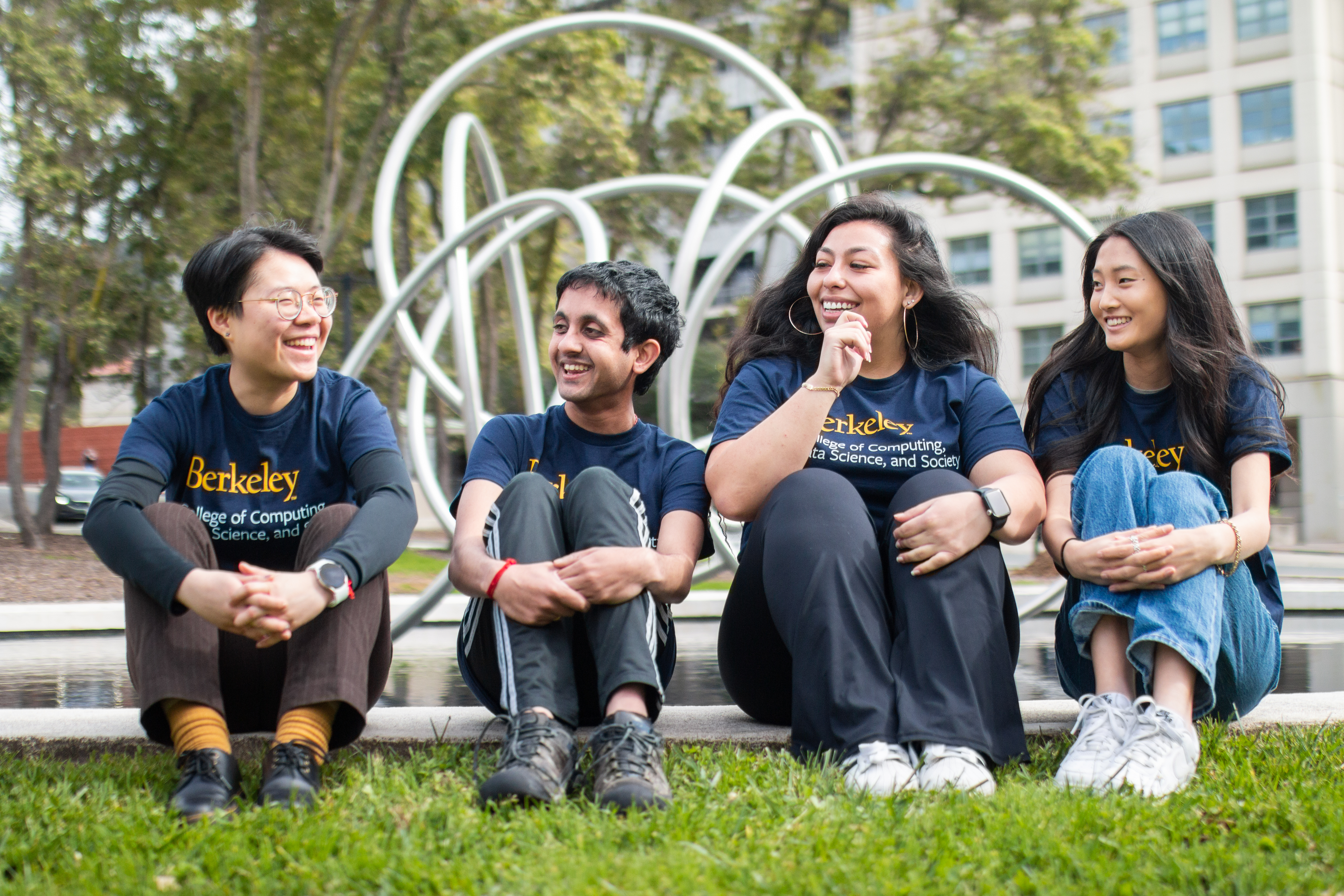 four students sitting, smiling for a picture