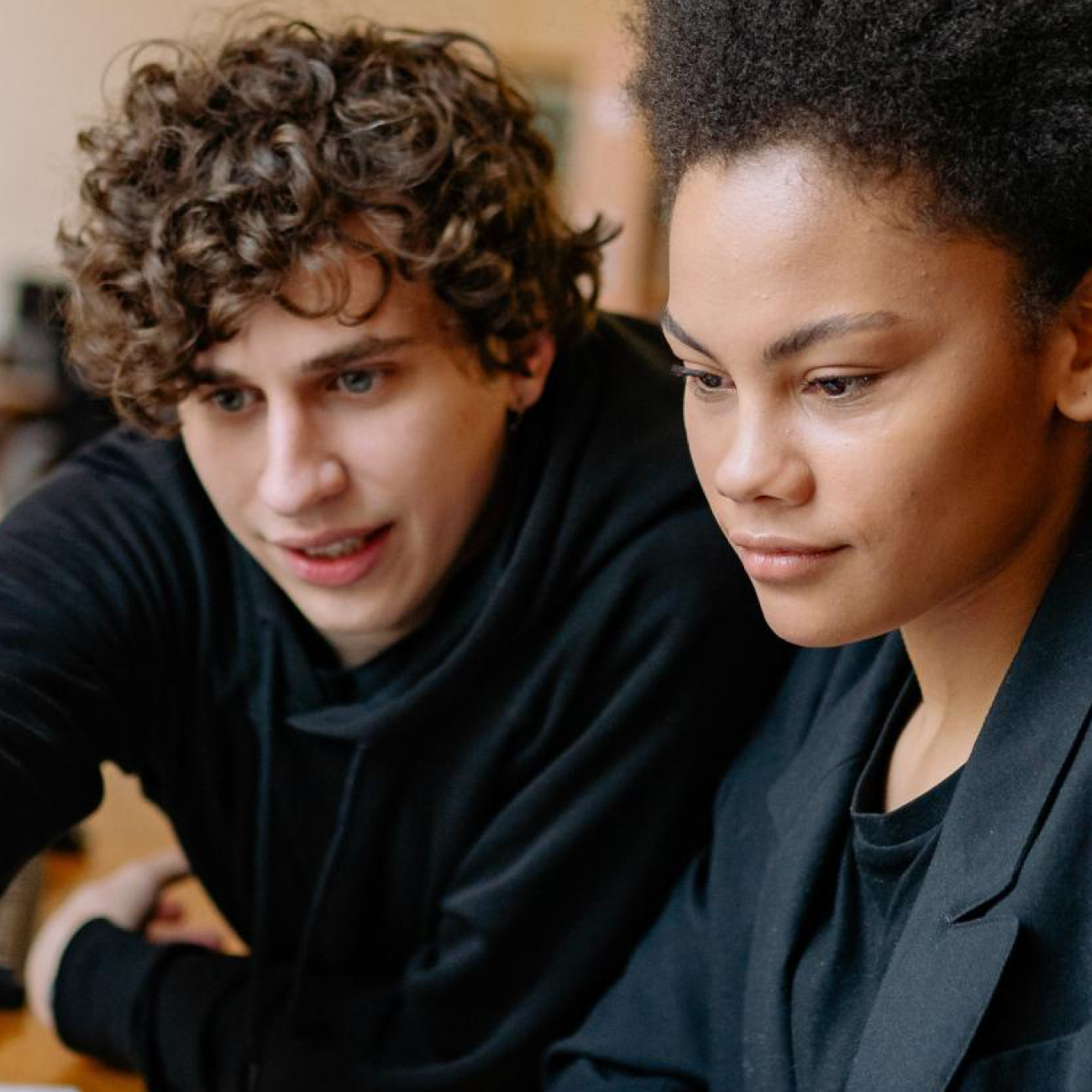 Two students sitting in a library while looking at a laptop together