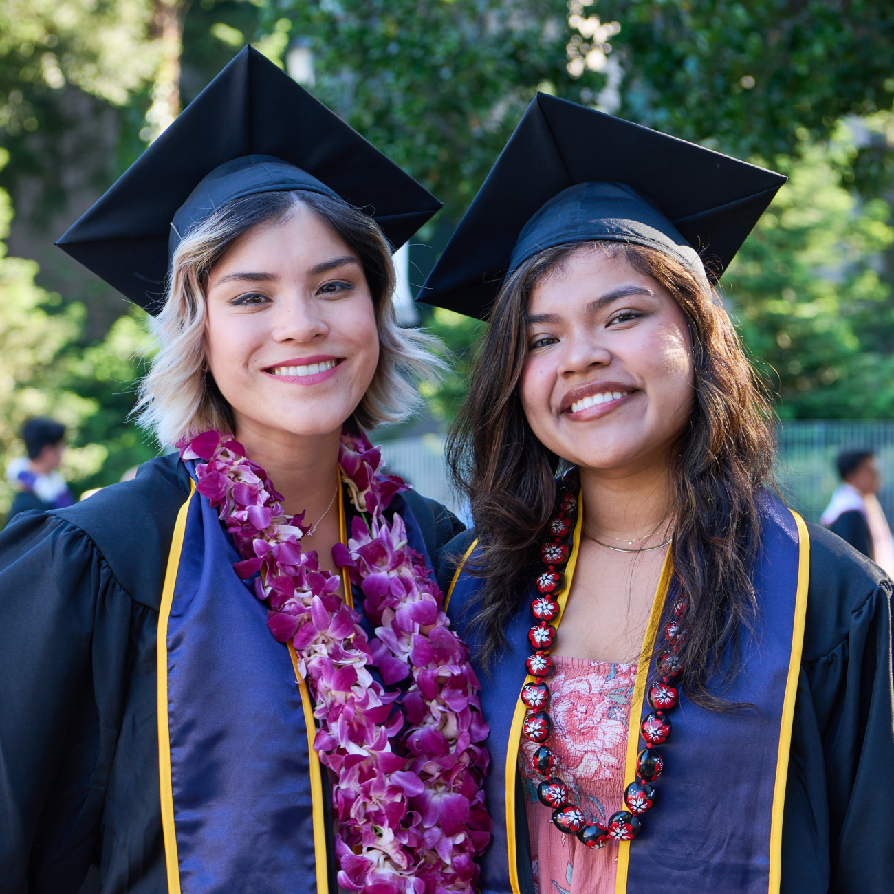 Two latina students pose in graduation caps and gowns
