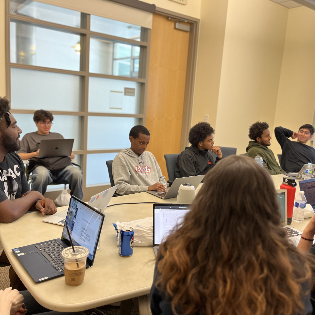 At a table, high school BUDS students sit with laptops as William Reed leads a group discussion.