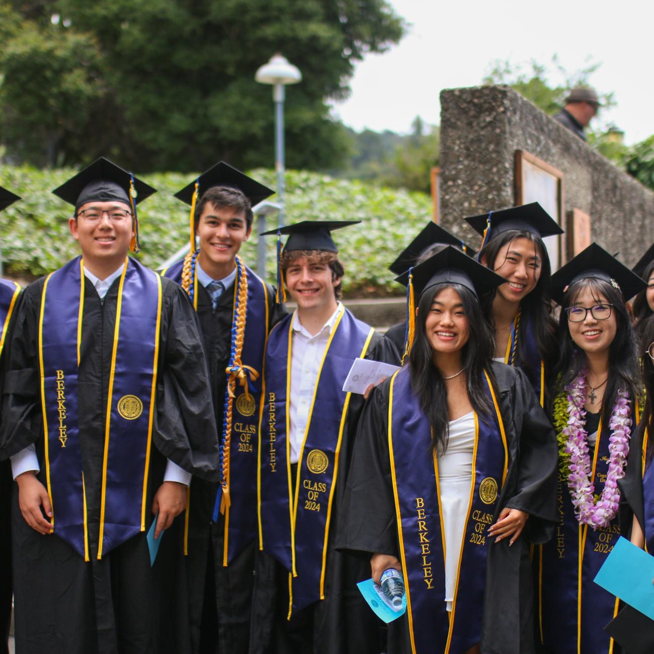 Students dressed in commencement regalia, smiling while posing for a picture at the 2024 CDSS Commencement Ceremony