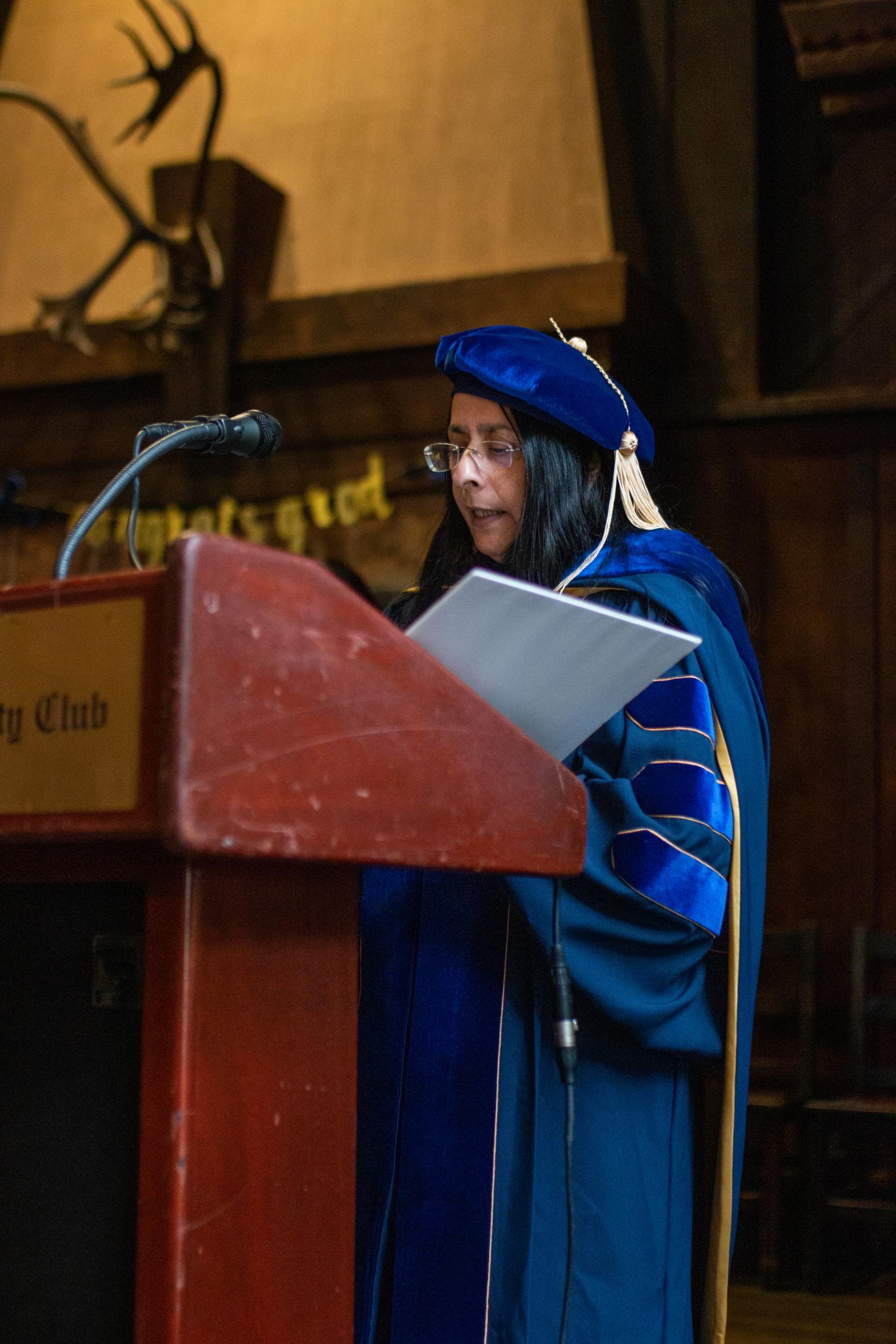 Professor Ani Adhikari speaks at lectern dressed in faculty graduation attire at 2024 Data Science Awards Reception 