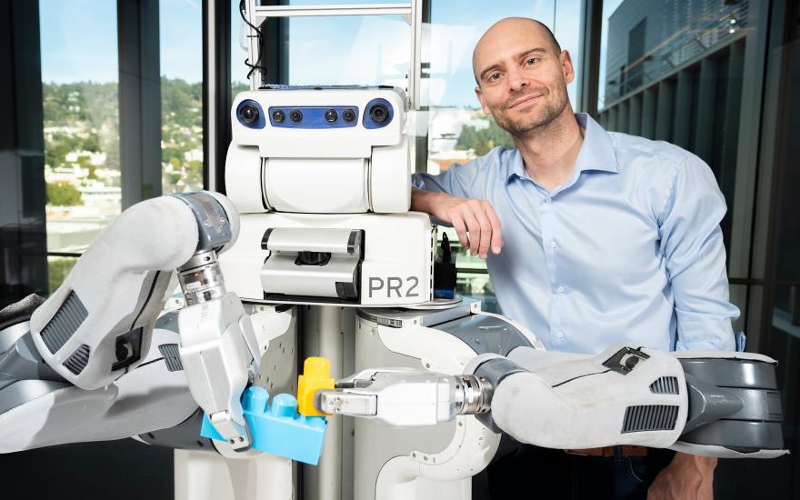 Pieter Abbeel standing next to BRETT, the Berkeley Robot for the Elimination of Tedious Tasks. (Photo by Adam Lau, Berkeley Engineering)