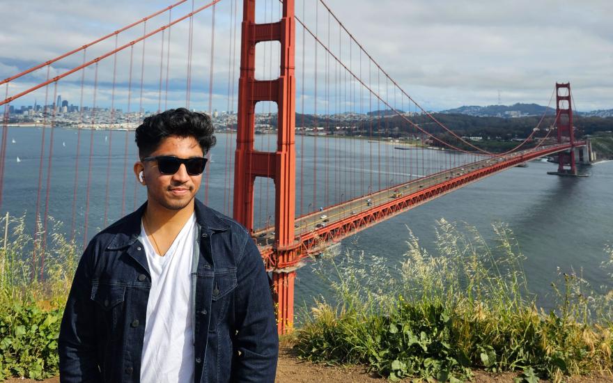 Image of Austin Pereira, smiling in front of the Golden Gate Bridge