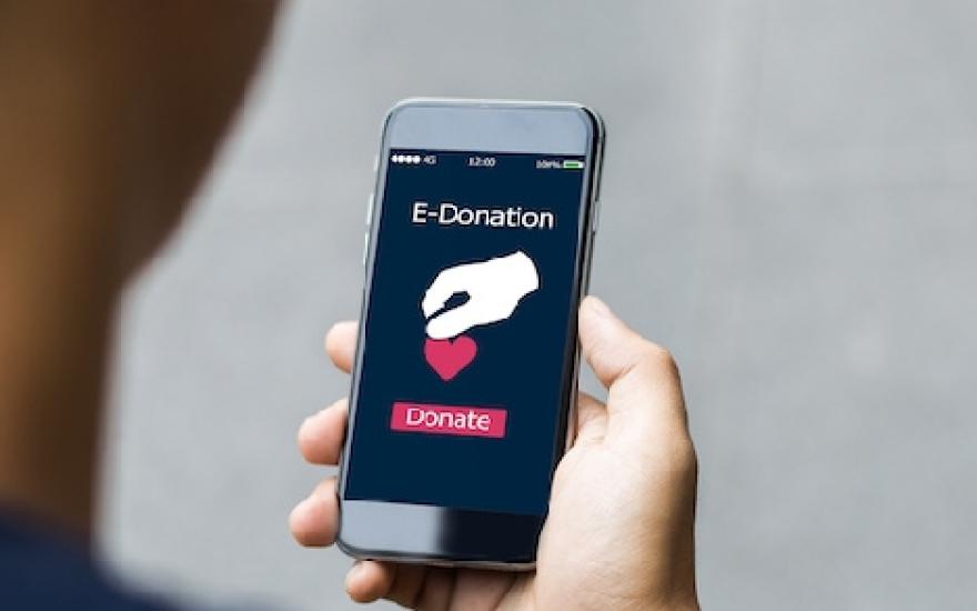 Over the shoulder shot of person holding phone with screen displaying "E-Donation"  
